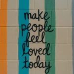 Art graffiti on a cinderblock wall "Make people feel loved today"