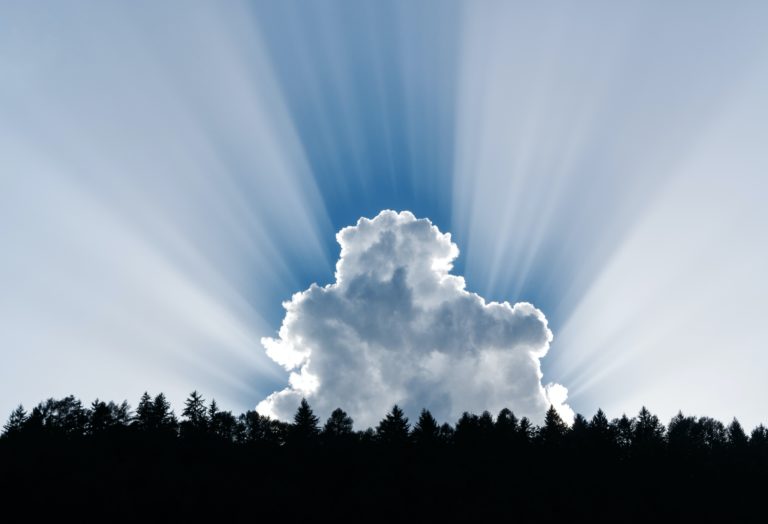 Sun bursting from behind a white cloud