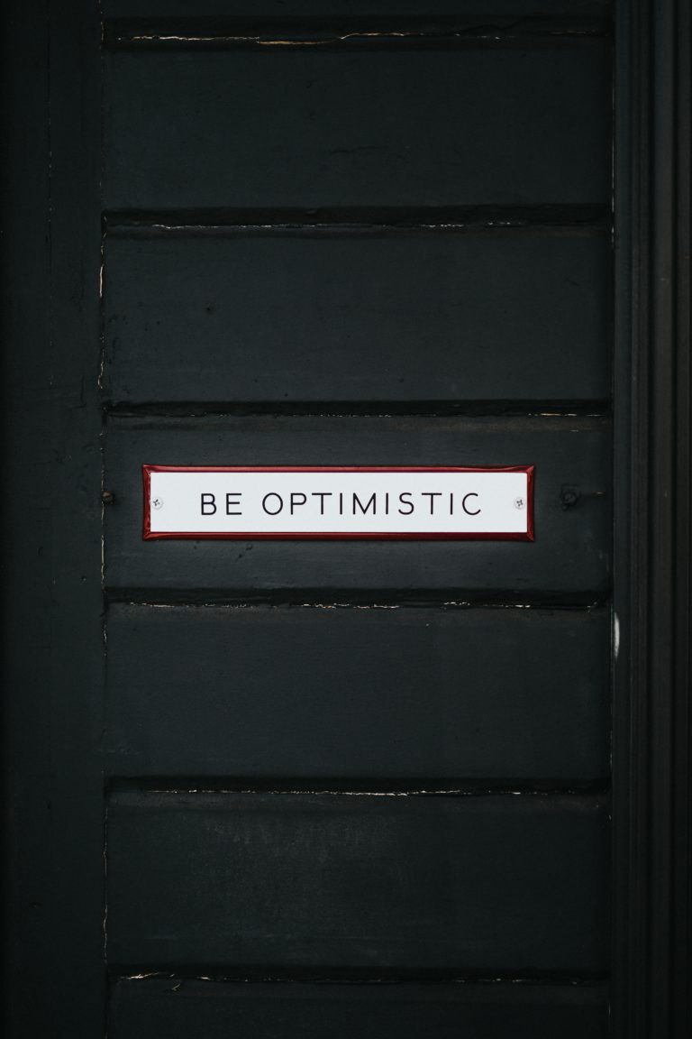 Black door with sign "Be Optimistic"